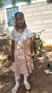 A girl stands outside her primary school building